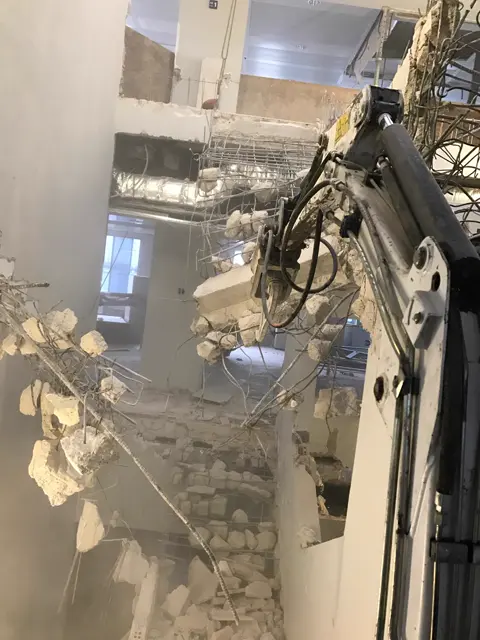 Escavatore con pinza al lavoro in una demolizione interna