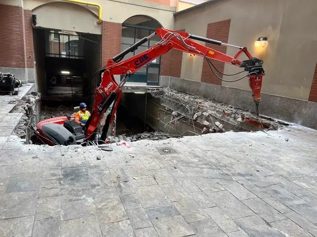 Escavatore in demolizione su copertura in un cortile milanese
