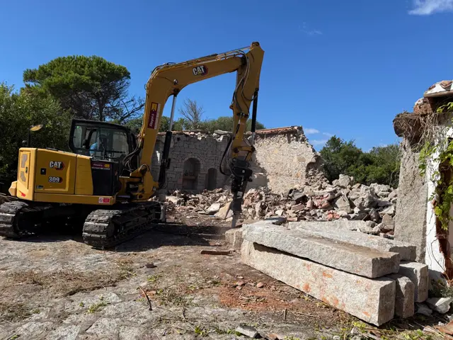 Escavatore al lavoro tra le murature demolite